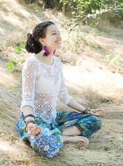 Woman profile portrait practicing meditation in park, sitting in lotus pose