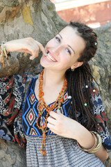 Smiling young woman portrait with dreadlocks hairstyle posing in a sunny outdoor