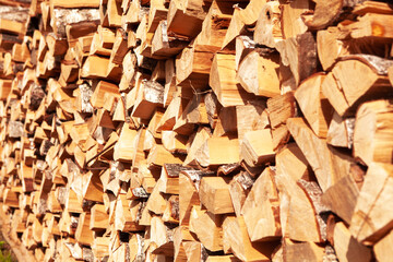 Textured firewood background of chopped wood for kindling and heating the house, a woodpile with stacked firewood. Concept of economic fuel crisis.