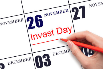 Hand drawing red line and writing the text Invest Day on calendar date November 26. Business and financial concept.