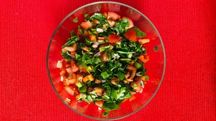 Mixed salad isolated, Turkish Coban salata or Shepherds salad in glass bowl on red isolated background, top view