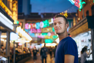 Portrait of man on evening illuminated street market. Tourist in Chinetown in Singapore..