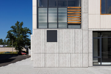 A modern building with a ventilation grate in the wall.