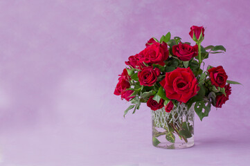 Red rose flowers in vase, green leaves, close up,