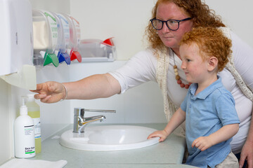 mother reaching for paper towel to wipe child's hands clean