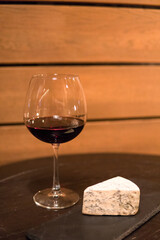 A glass of red wine and a head of cheese on a plate