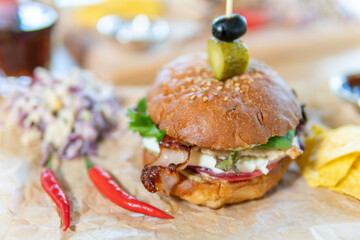 Beef patty burger. bacon, cheese, tomato, greens, pickle, red cabbage salad, hot pepper, fries, corn chips, ketchup