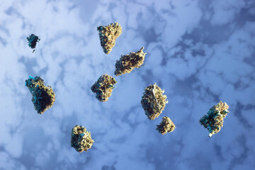 Dry buds of medical marijuana levitate against a marble background in blue lighting.  The...