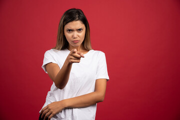 Young woman pointing at something on red background