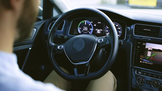 Vehicle parallel parking by itself in suburban town street. Self-steering automatic computer vision auto turning wheel and parking on spot. Man in futuristic automated electric car