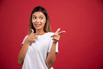 Young woman showing her fingers on red background