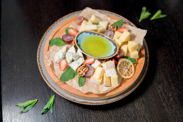 Cheese assorted with honey, decorated with fresh fruits, strawberries, grapes, lemon, walnut