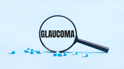 On a blue background, white and blue capsules with pills and a black magnifying glass with the text GLAUCOMA. Medical concept.