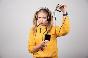 Beautiful blonde woman looking at cords on gray background