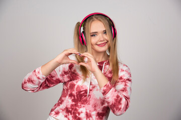 Young woman in pink outfit making heart sign