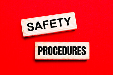On a bright red background, there are two light wooden blocks with the text SAFETY PROCEDURES