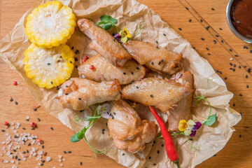 Chicken wings with barbecue sauce, hot pepper, microgreens, corn on a wooden board
