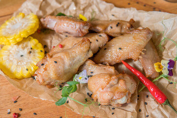 Chicken wings with barbecue sauce, hot pepper, microgreens, corn on a wooden board