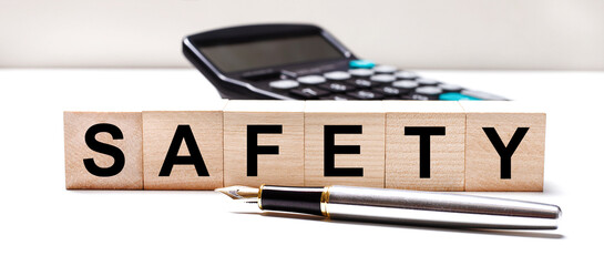 The light table has a black calculator, a fountain pen, and wooden cubes with the text SAFETY. Business concept