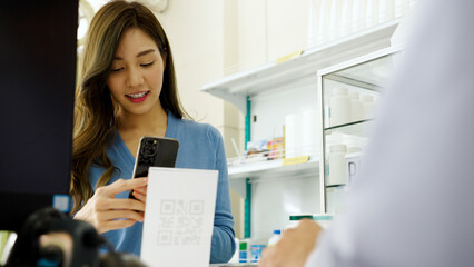 Asian woman pays via QR code with mobile phone in pharmacy