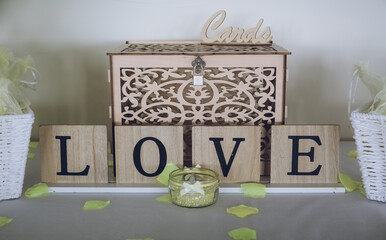 A sign reading love on a table at a wedding reception in front of a wedding card collection box
