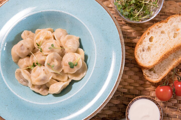 Dumplings with meat, sour cream, microgreens