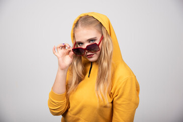 Portrait of pretty girl in yellow hoodie posing with glasses