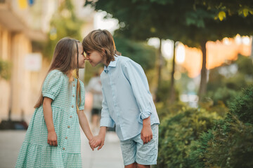 Fototapeta premium A boy and a girl walking together and holding each other hands, look at each other.