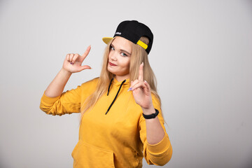 Portrait of woman in hoodie pointing up with index fingers