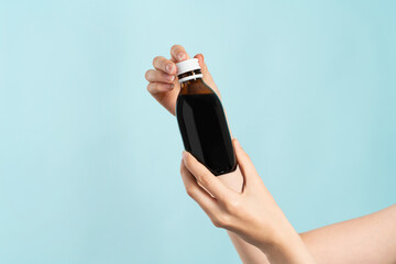 Image of hands holding a brown bottle of liquid cold medication. Bottle without label for product...