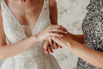 Bride in white wedding dress holding mother's hands