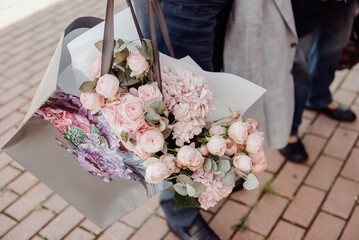 Bouquet of roses, pink in a kraft paper bag in hands