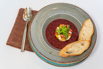 Gaspacho soup on round wooden tray over white marble tabletop. Bowl of traditional spanish cold soup puree gazpacho on light marble background
