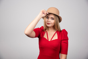 Young beautiful woman in red dress touching her hat