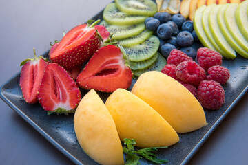 Healthy fresh fruit salad in glass bowl on white wooden background
