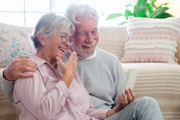 Happy beautiful caucasian senior couple sitting on the floor at home using smart phone in video chat, old people and new technologies concept