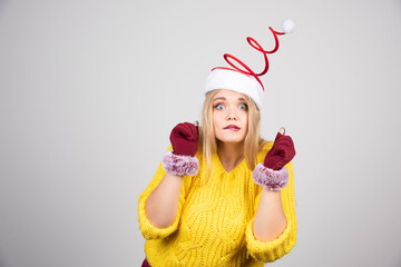 Funny girl in a yellow sweater and Santa's hat posing