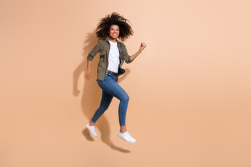 Fototapeta na wymiar Full length body size view of pretty cheerful thin sportive girl jumping running isolated over beige pastel color background