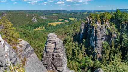 Panoramic over monumental Bastei sandstone pillars, rock formation and stacks surrounded by ancient forests at Kurort Rathen village in the national park Saxon Switzerland by Dresden, Saxony, Germany.