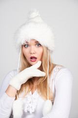 Portrait of blonde woman in winter outfit standing on gray background