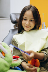 Child brushing teeth in a dentist chair