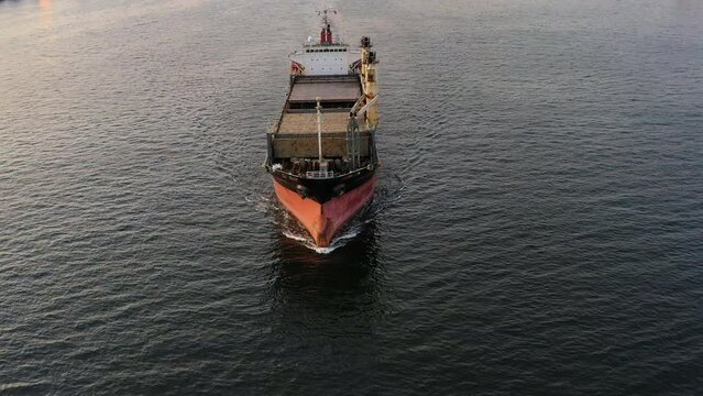 Cargo rusty ship sails on the sea at sunset. A bulk carrier is a merchant ship designed to transport unpackaged bulk cargo (grain, ore, coal). Drone view