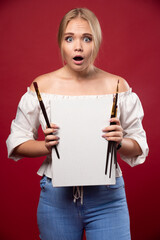 Blonde artist showing her artwork with hesitation and looks for reviews