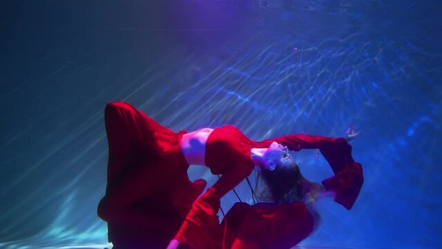Slow Motion Female figure in a dark red dress underwater.