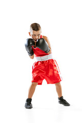 Portrait of active boy, beginner boxer in sports gloves and red uniform isolated on white background. Concept of sport, movement, studying, achievements, lifestyle.