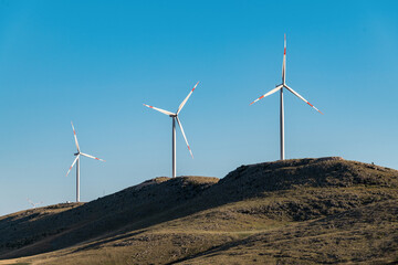 clean electricity producing wind turbine or windmill built on a windy mountain ridge