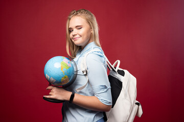 Blonde studentgirl holds a globe and looks positive
