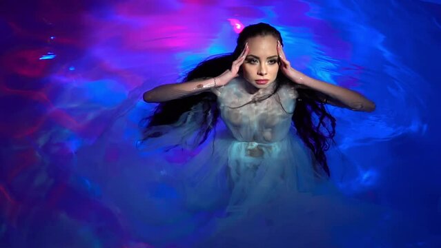 Slow Motion Underwater woman portrait with white dress into the sea.