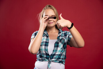 Young blonde model looking through a polaroid film tube and having fun
