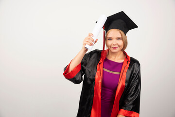 Female student in gown holding diploma on white background